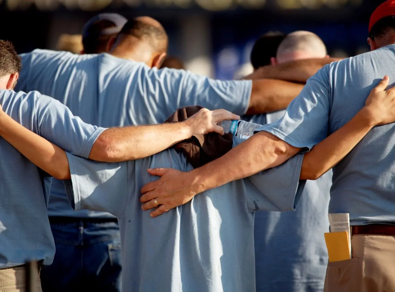 people standing arm-in-arm together praying