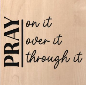 wood sign that says "Pray on it, over it, through it"