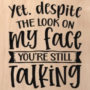 wood sign that says "Yet. Despite the look on my face you're still talking"