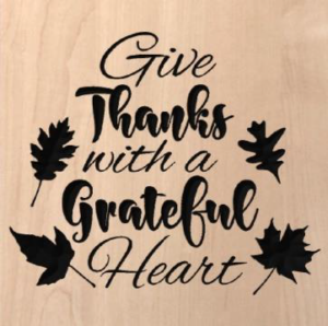 wood sign that says "give thanks with a grateful heart" with leaves around the words