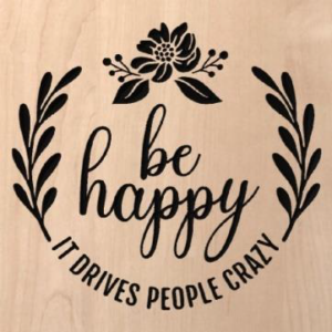wood sign that says "be happy, it drives people crazy" with vines and a flower at the top