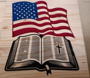 wood sign with american flag waving above an open Bible