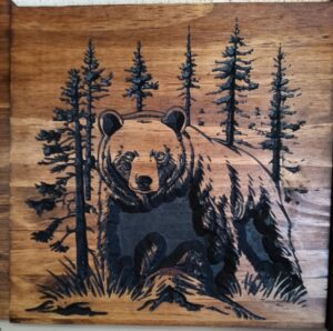 wood sign with realistic bear standing in front of pine trees