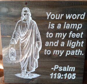 wood sign with Jesus holding a lamp. Text on the right side that says: "Your word is a lamp to my feet and a light to my path. - Psalm 119:105"